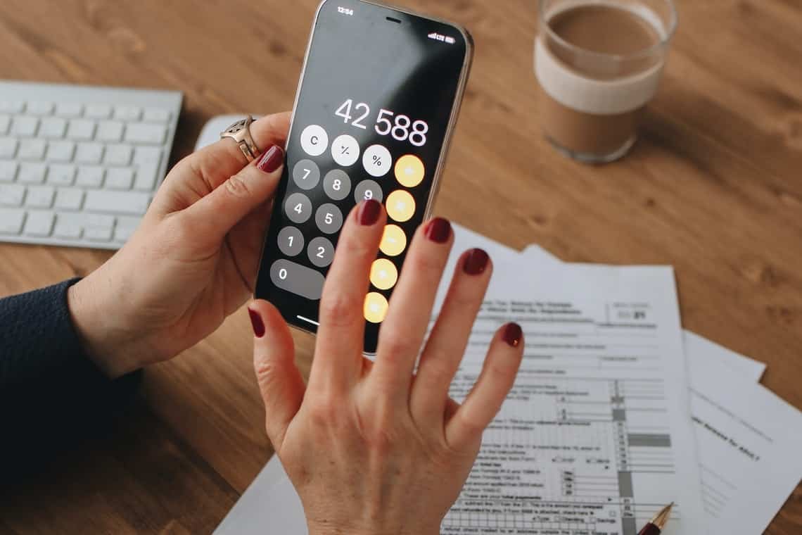 A person calculating tax on mobile- Tax and GST Requirements for Rideshare Drivers in New Zealand